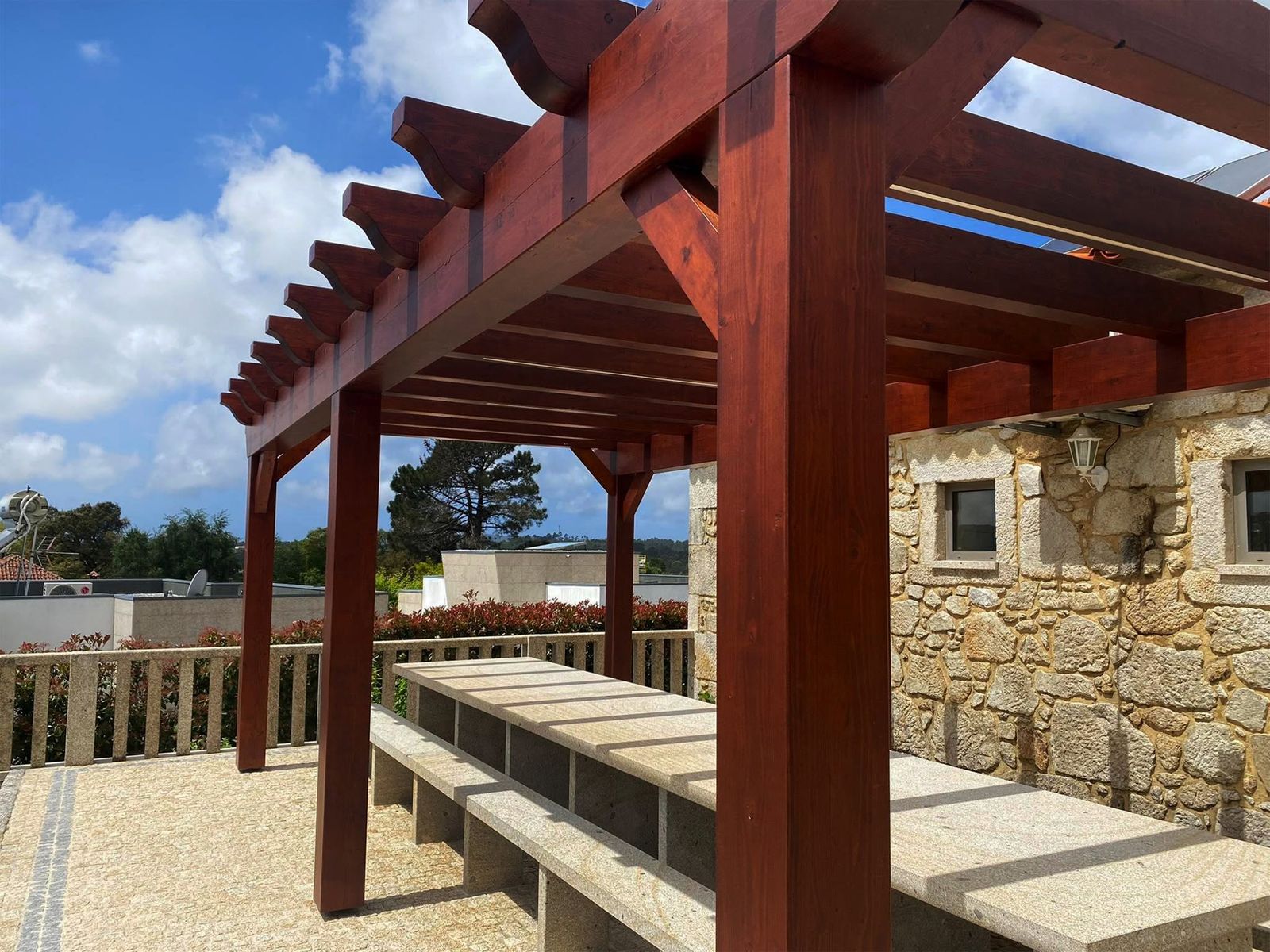 Pérgola de madeira sobre um terraço com muro de pedra